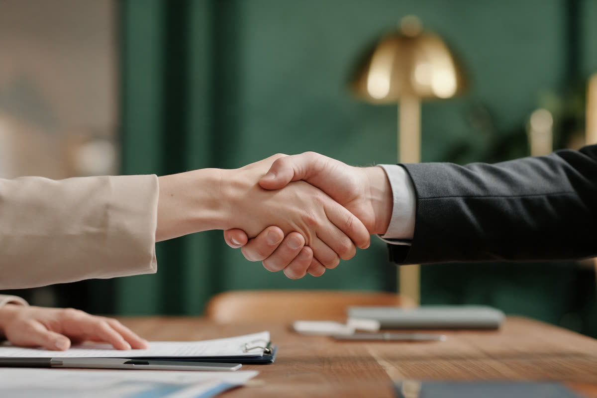 Partners shaking hands Two people shaking hands across a wooden conference table